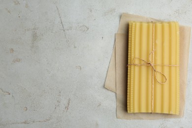 Photo of Uncooked lasagna sheets tied with rope on light grey table, top view. Space for text