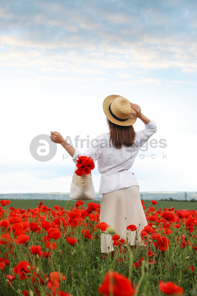 Photo of Woman with handbag and poppy flowers in beautiful field