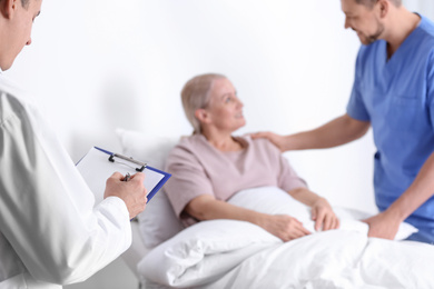 Photo of Doctor and male nurse visiting patient in hospital ward, closeup