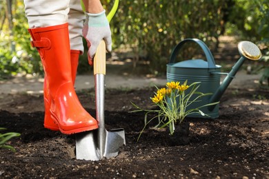 Photo of Woman digging soil with shovel outdoors, closeup. Gardening time