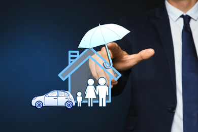 Insurance concept - umbrella demonstrating protection. Man using virtual screen with illustrations, closeup