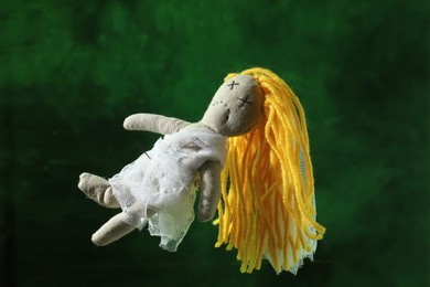 Female voodoo doll with pins and smoke on green background