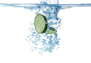 Photo of Slices of fresh cucumber falling into water on white background, closeup