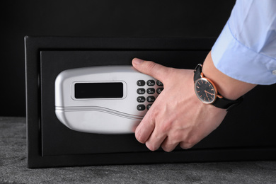 Man opening black steel safe with electronic lock, closeup