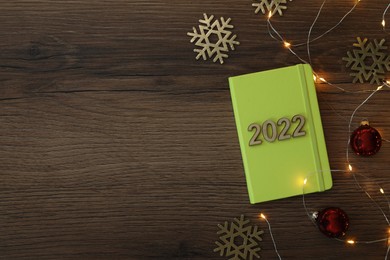 Stylish planner and Christmas decor on wooden background, flat lay with space for text. 2022 New Year aims