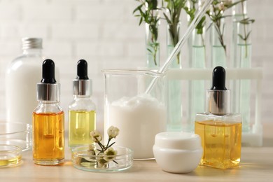 Organic cosmetic products, natural ingredients and laboratory glassware on wooden table, closeup