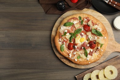 Photo of Pita pizza with prosciutto, pineapple, grilled tomatoes and egg on wooden table, flat lay. Space for text