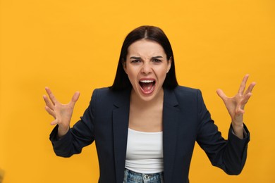 Angry young woman on yellow background. Hate concept