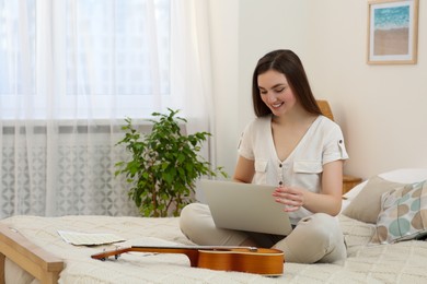 Photo of Woman learning to play ukulele with online music course at home. Space for text