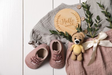Flat lay composition with children's clothes, shoes and toy on white wooden table