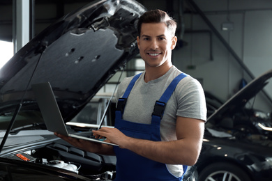 Mechanic with laptop doing car diagnostic at automobile repair shop