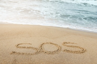 Message SOS drawn on sand near sea