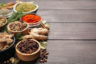 Different natural spices and herbs on wooden table. Space for text