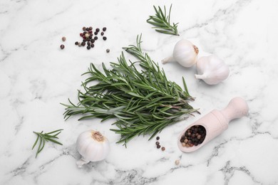 Sprigs of rosemary, garlic and scoop with peppercorns on white marble table, flat lay
