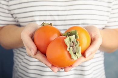 Woman holding delicious fresh persimmon fruits, closeup