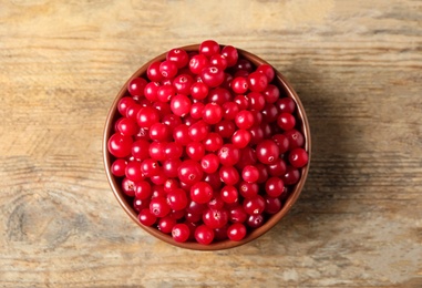 Photo of Tasty ripe cranberries on wooden table, top view