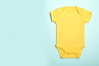 Child's bodysuit on light blue background, top view. Space for text