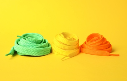 Different colorful shoe laces on yellow background