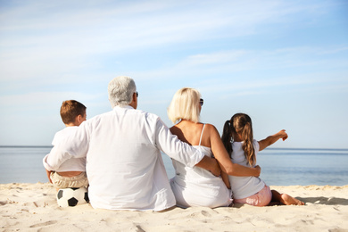 Cute little children with grandparents spending time together on sea beach, back view
