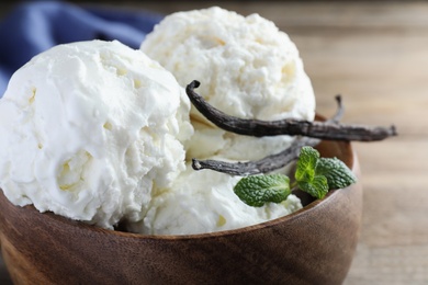 Yummy vanilla ice cream in wooden bowl, closeup
