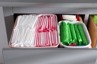 Open cabinet drawer with menstrual pads, tampons and pantyliners, closeup