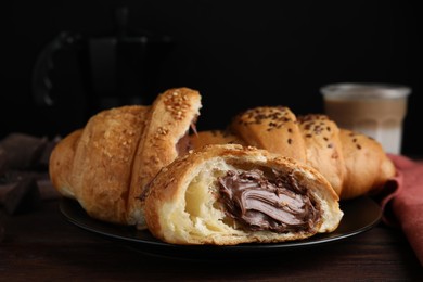 Tasty croissants with chocolate and sesame seeds on wooden table, closeup