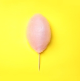 Photo of Sweet pink cotton candy on yellow background, top view