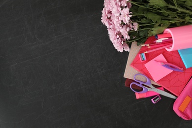 Different school stationery and beautiful pink flowers on blackboard, flat lay with space for text. Happy Teacher's Day