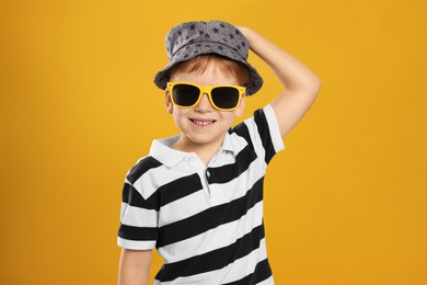 Cute little boy with sunglasses on yellow background
