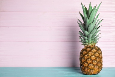 Photo of Fresh ripe juicy pineapple on light blue wooden table. Space for text