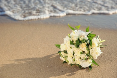 Beautiful wedding bouquet on sandy beach near sea