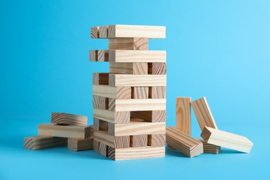 Jenga tower made of wooden blocks on light blue background