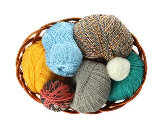 Different balls of woolen knitting yarns in wicker basket on white background, top view