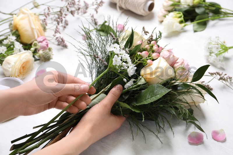 Florist making beautiful bouquet at white table, closeup