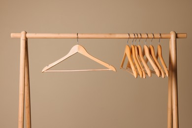 Photo of Clothes hangers on wooden rack against beige background
