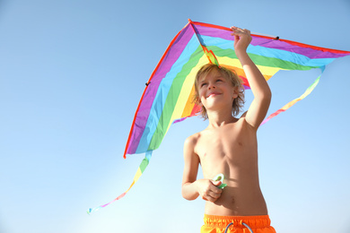 Cute little child playing with kite on sunny day. Beach holiday