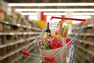 Shopping cart with different groceries in supermarket