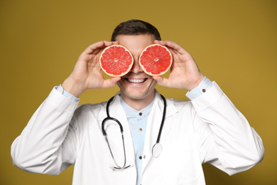 Nutritionist posing with halves of ripe grapefruit on yellow background