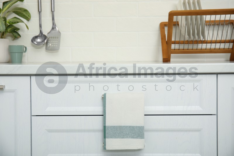 Photo of Clean towel hanging on drawer handle in kitchen