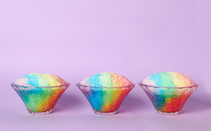 Rainbow shaving ice in glass dessert bowls on violet background