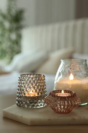 Set of scented candles on wooden table in room