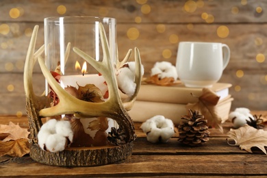 Stylish holder with burning candle and autumn decor on wooden table. Space for text