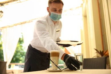 Waiter serving beverages in restaurant. Catering during coronavirus quarantine