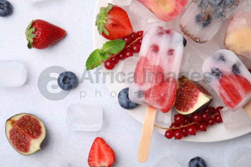 Flat lay composition with fruit and berry ice pops on white table