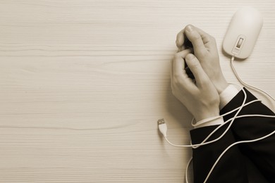 Image of Top view of internet addicted woman with her hands tangled in cable of computer mouse at wooden table, space for text. Sepia effect.