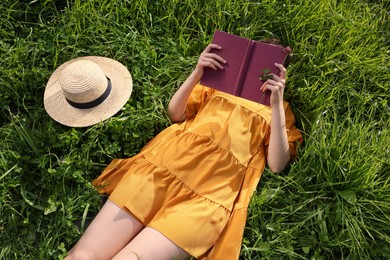Woman reading book on green meadow, above view