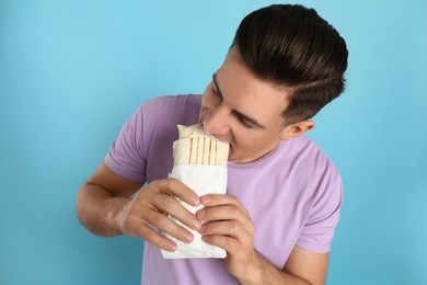 Photo of Man eating delicious shawarma on turquoise background