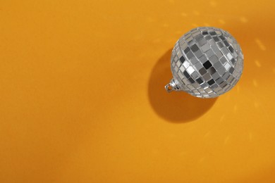 Bright shiny disco ball on orange background, top view. Space for text