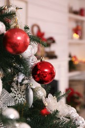 Beautiful Christmas tree with baubles in room, closeup. Interior design