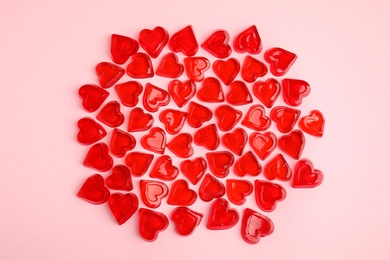 Sweet heart shaped jelly candies on pink background, flat lay